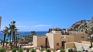 A coastal resort with buildings, palm trees, and a view of the sea. - Exquisite Escape (Cabo San Lucas)
