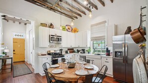 A modern kitchen with white cabinets, stainless steel appliances, and a wooden dining table set for six. - Beautifully renovated 3BR house, off street parking in the Marigny Triangle (New Orleans)