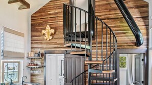 A modern kitchen with wooden beams, a black spiral staircase, and a rustic decor. - Beautifully renovated 3BR house, off street parking in the Marigny Triangle (New Orleans)
