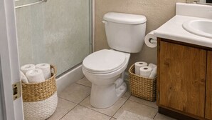 Et badeværelse med toilet, håndvask, håndklædestativ og bruseområde.