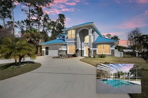 A large, modern house with a blue roof, a covered swimming pool, and a well-maintained lawn.