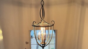 Ein Kronleuchter hängt in einer Diele mit einem Fenster über einer Tür.