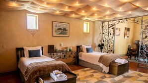 A hotel room with two beds, a patterned rug, and a decorative ceiling. - The Vineyard House in the Pastures of Heaven (Corral de Tierra)