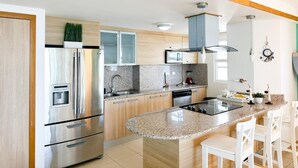 A modern kitchen with stainless steel appliances, wooden cabinets, and a granite countertop island.