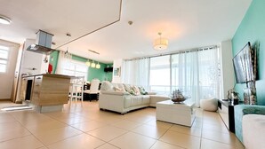 A spacious living area with a sofa, a dining table, and a kitchen area.