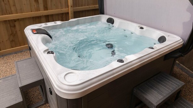 Ein Whirlpool mit einer Holzterrasse und Stufen, die hinaufführen.
