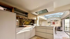 A modern kitchen with a skylight, built-in appliances, and a view to the outdoors. - Beautiful 5-Bed Regency Home in Montpellier (Gloucestershire)