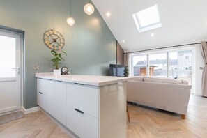 A modern kitchen with a central island, a large window, and a view of the city. - Comfortable & Contemporary 5-Bed 3 Bathroom Home (Gloucestershire)