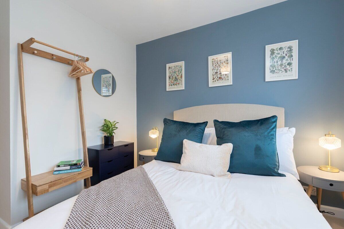 Une chambre à coucher comprenant un lit, des tables de chevet, un miroir et des œuvres d’art murales.