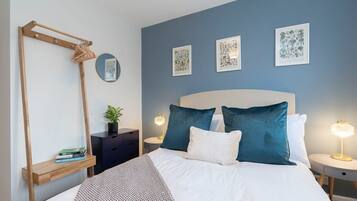 Une chambre à coucher comprenant un lit, des tables de chevet, un miroir et des œuvres d’art murales.