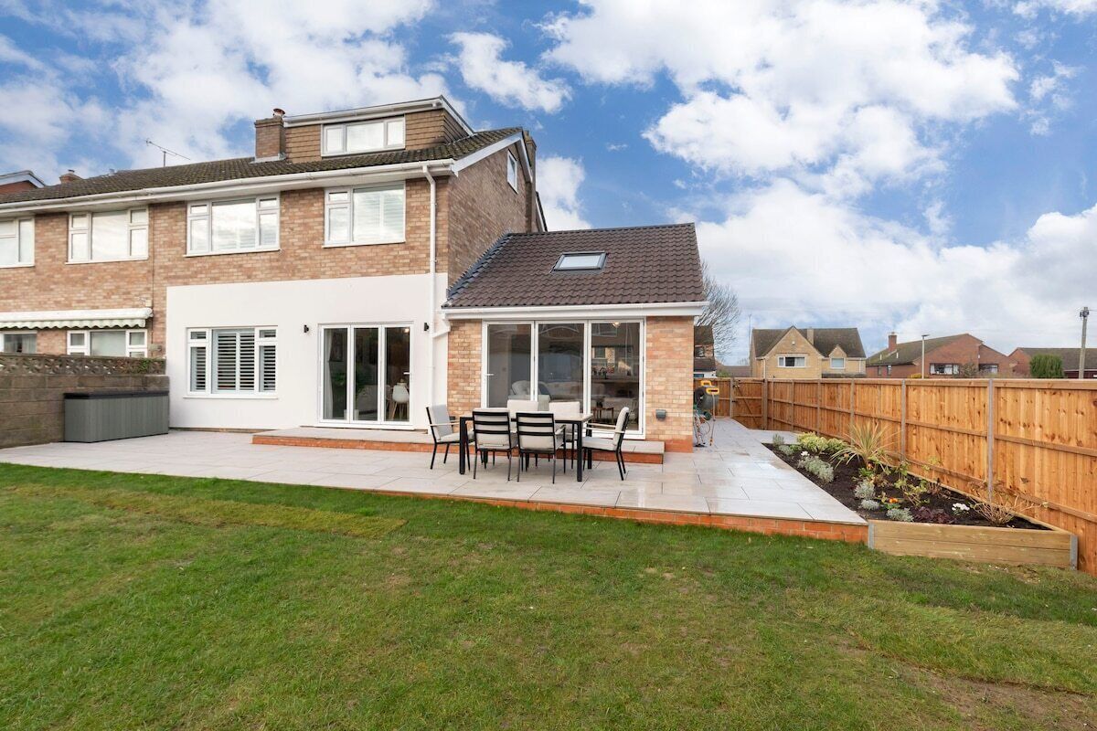 A two-story house with a patio, a covered outdoor seating area, and a fenced backyard.