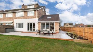 A two-story house with a patio, a covered outdoor seating area, and a fenced backyard.