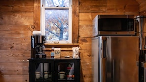 Une cuisine avec des murs en bois, un réfrigérateur en acier inoxydable, un four à micro-ondes et une machine à café.