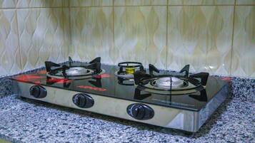A gas stove with four burners and a control panel, set on a granite countertop.