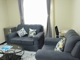 A living room with two grey sofas, a glass coffee table, and a small side table.