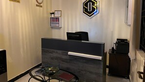 A reception area with a reception desk, two clocks, a framed certificate, and a decorative glass bowl on a table. - Oltotoi suites (Kitengela)
