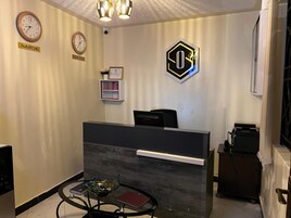 A reception area with a reception desk, two clocks, a framed certificate, and a decorative glass bowl on a table.