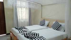 A room with two beds, each with white bedding and striped pillows. - Oltotoi suites (Kitengela)