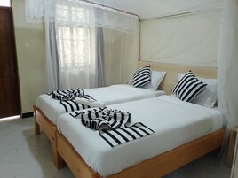 A room with two beds, each with white bedding and striped pillows.