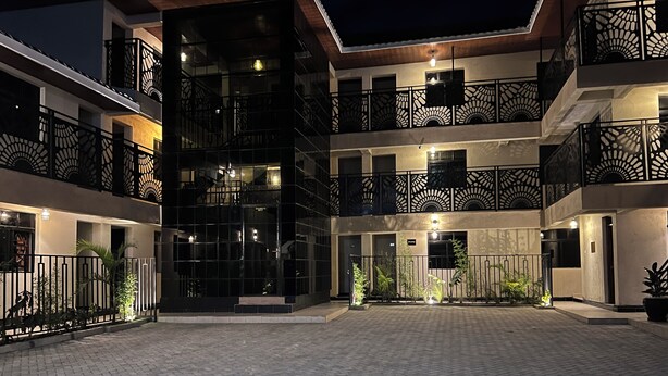A multi-story building with a courtyard, featuring balconies with intricate railings and a central open space with potted plants. - Oltotoi suites (Kitengela)