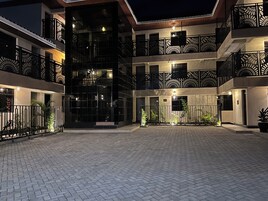 A multi-story building with a courtyard, featuring balconies with intricate railings and a central open space with potted plants.