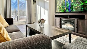 Sala de estar com sofá, mesa de centro e televisão de tela plana fixada em um armário de madeira.