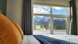 Quarto de hotel com uma grande janela e vista para as montanhas.