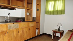 A compact kitchen with wooden cabinets, a sink, and a small table with a lamp. - SPACIOUS 6-BEDROOM SINGLE LEVEL LODGE IN MEDINA, WIFI, AC, PARKING LOT, GARAGE (Medina)