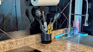 A kitchen with a granite countertop, a black induction cooktop, a stainless steel sink, and a roll of paper towels. - Modern Oceanfront Apartment  (Arecibo)