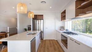 Una cocina moderna con una isla central, electrodomésticos de acero inoxidable y un amplio ventanal con vistas al exterior.
