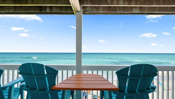 Une terrasse en bois avec une table et deux chaises, d’où l’on a une vue sur l’océan.