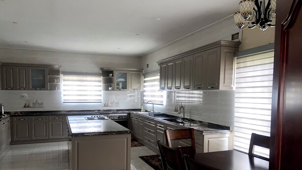 A spacious kitchen with a central island, built-in cabinets, and a dining area with a wooden table and chairs.