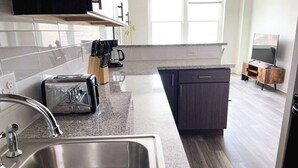 A modern kitchen with a stainless steel sink, a toaster, and a coffee maker. - Sleepover | Elegant 1BD/1BA + Gym - Cincinnati (Cincinnati)