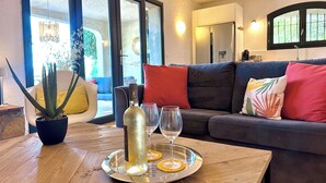 Un salon moderne avec un canapé, une plante en pot, une bouteille de vin et un plateau avec un verre.
