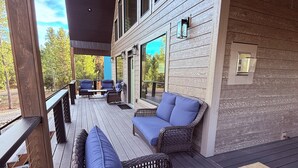 A covered outdoor deck with wicker furniture and a wooden table.