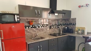 A compact kitchen with a red refrigerator, a microwave, a gas stove, and dark cabinets. - ⭐ Charming Apartment in Marrakech (Marrakech)