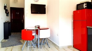 A compact kitchen with a dining table, chairs, a red refrigerator, and a flat-screen TV mounted on the wall. - ⭐ Charming Apartment in Marrakech (Marrakech)