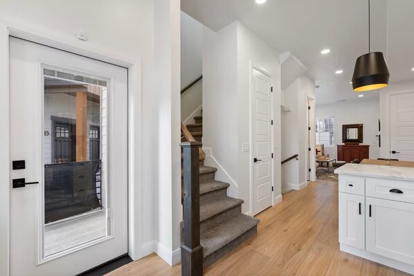 A modern interior with a staircase, white cabinetry, and a pendant light.