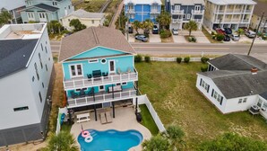 A coastal residential area with a prominent turquoise house featuring a balcony and a swimming pool. - The Turquoise Turtle -Private Pool, Hot Tub, Ocean View, 2nd Row, 4BR, Kids Area (Carolina Beach)