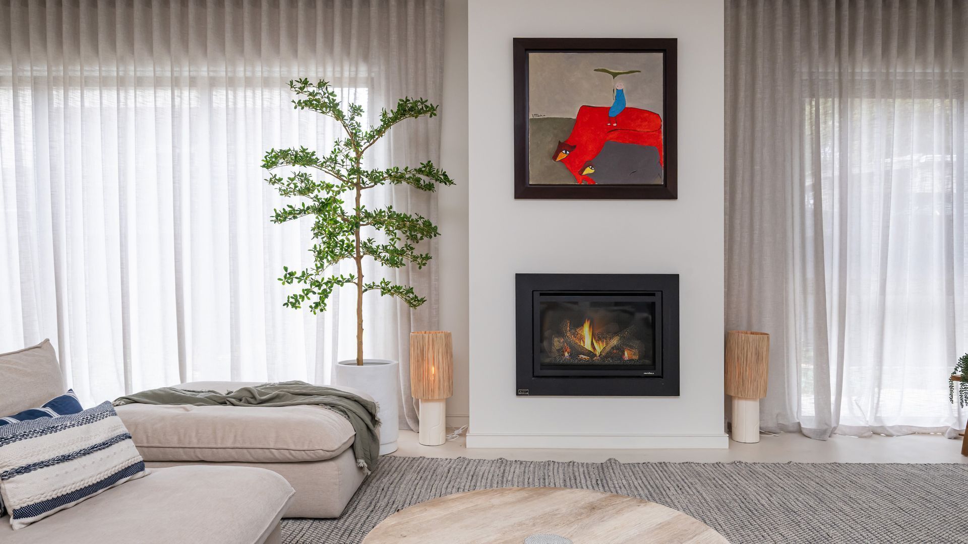 Ein Wohnzimmer mit Sofa, Kamin, einem gerahmten Kunstwerk und einer Pflanze.