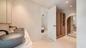 Een moderne badkamer met twee grote wasbakken, een inloopdouche en een houten kast met ingebouwde planken.
