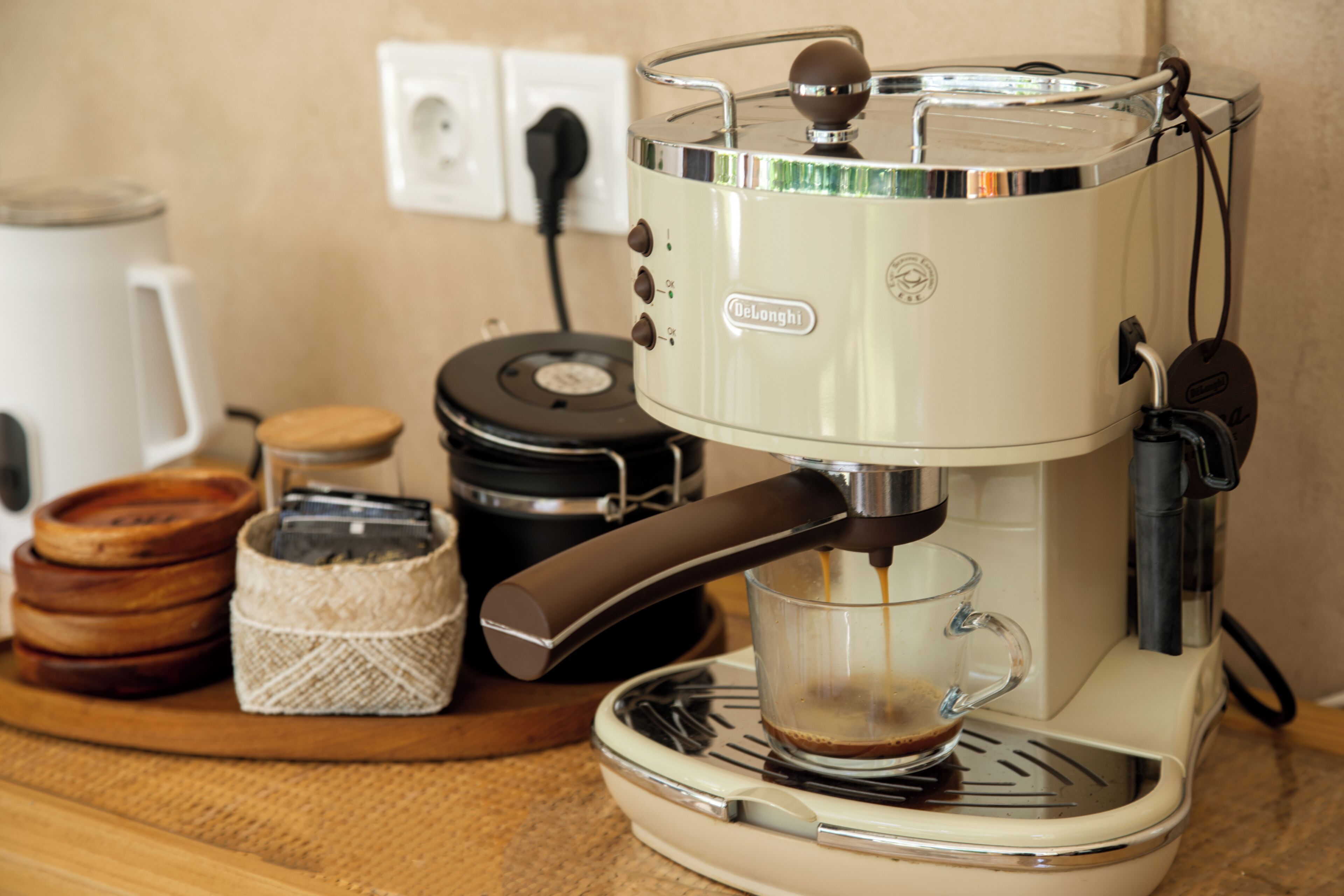 A coffee machine with a glass carafe, a coffee pot, and a cup on a kitchen counter.