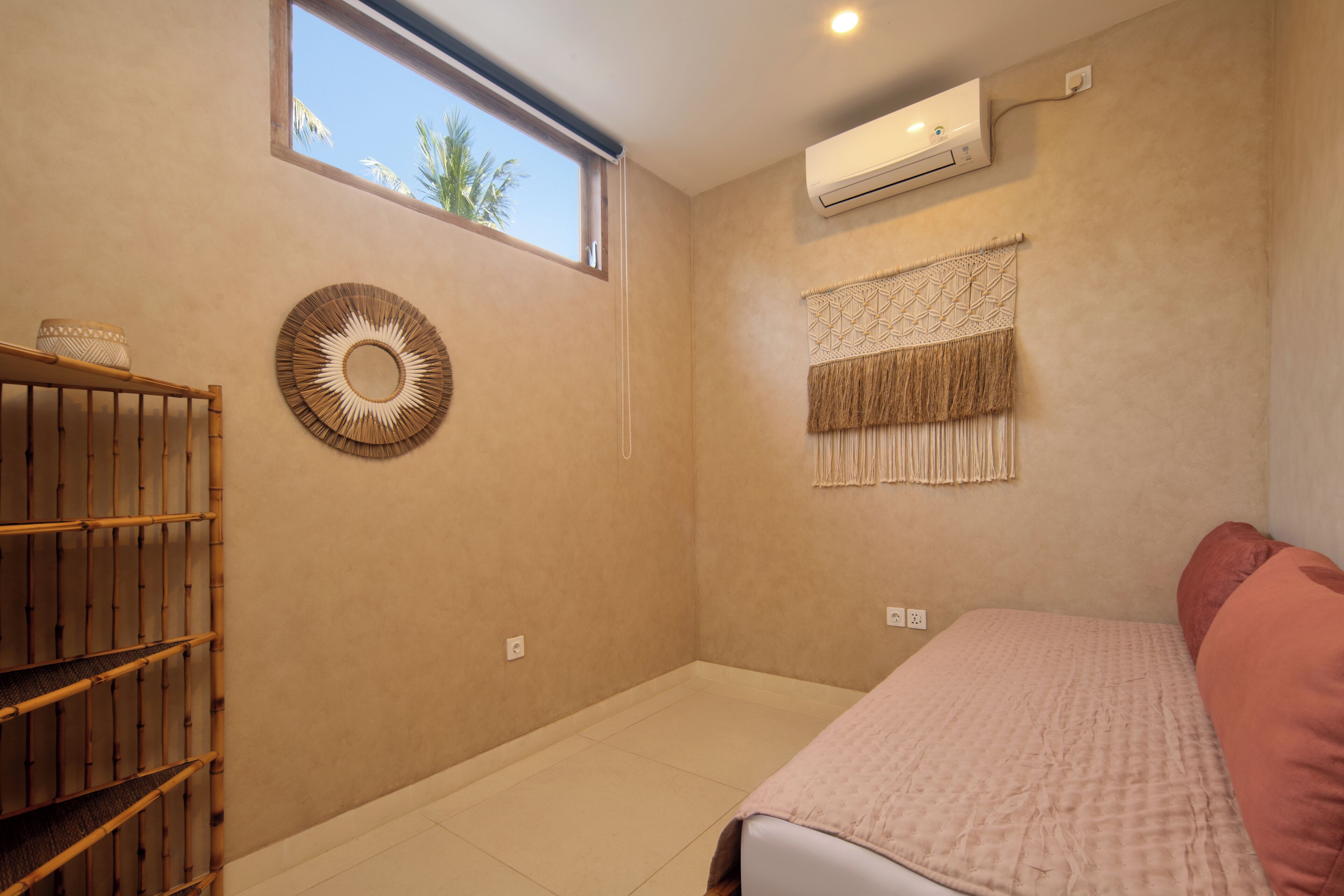 Ein Zimmer mit einem Bett, einem Fenster, einer Klimaanlage und einer wandmontierten Makramee-Dekoration.