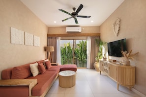 A modern living room with a sofa, a coffee table, a TV, and a ceiling fan.