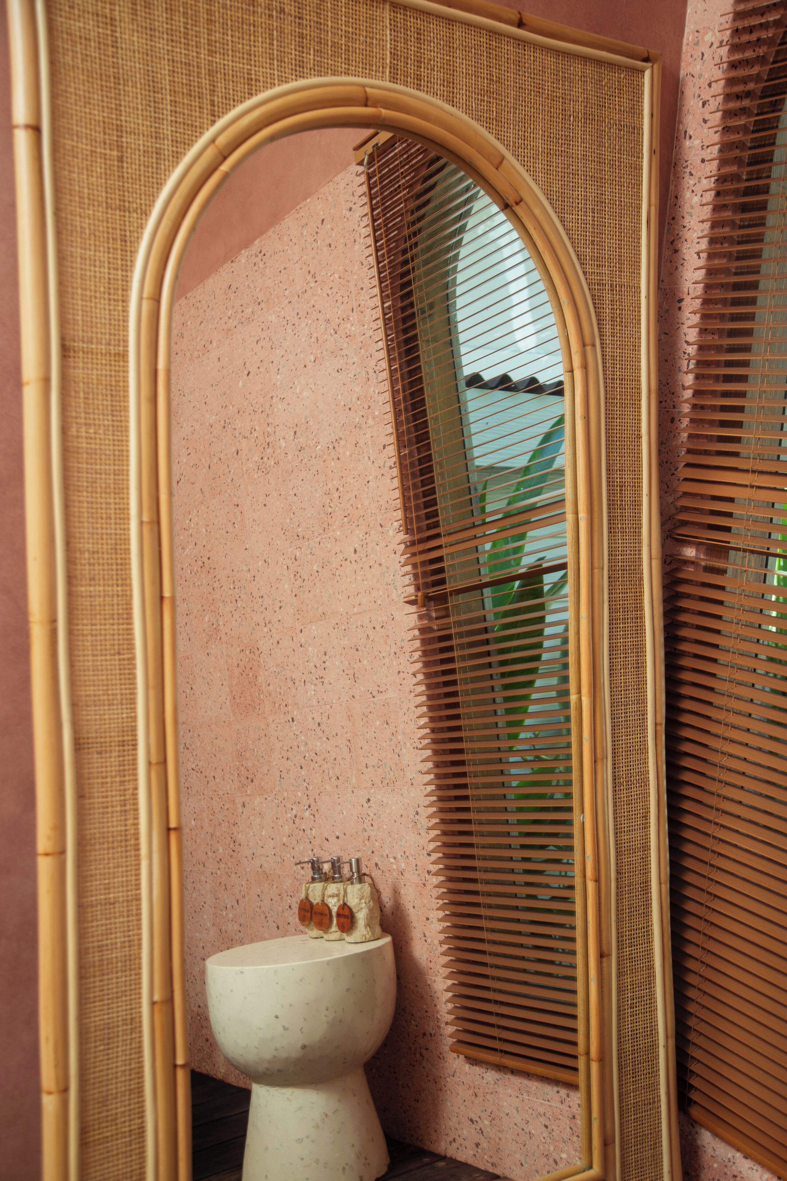 A bathroom with a large mirror, a sink, and a window with blinds.