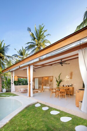 A modern outdoor living area with a pool, a dining set, and a seating area with a view of the pool. - Gili Boho Villas (Gili Trawangan)