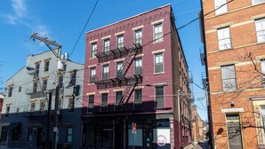 A red brick building with a fire escape, a storefront with a pink sign, and a clear blue sky. - Modern Condo in the heart of Over-The-Rhine (Cincinnati)