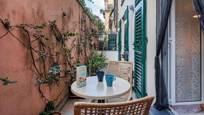 Un petit espace extérieur aménagé avec une table ronde, des chaises en osier et une boîte de biscuits.