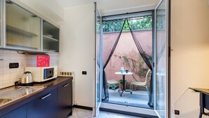 Une cuisine compacte équipée d’un four à micro-ondes, d’une bouilloire et d’une petite table avec des chaises.