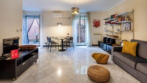 Un salon moderne comprenant un coin repas, un canapé, une bibliothèque et une grande fenêtre.